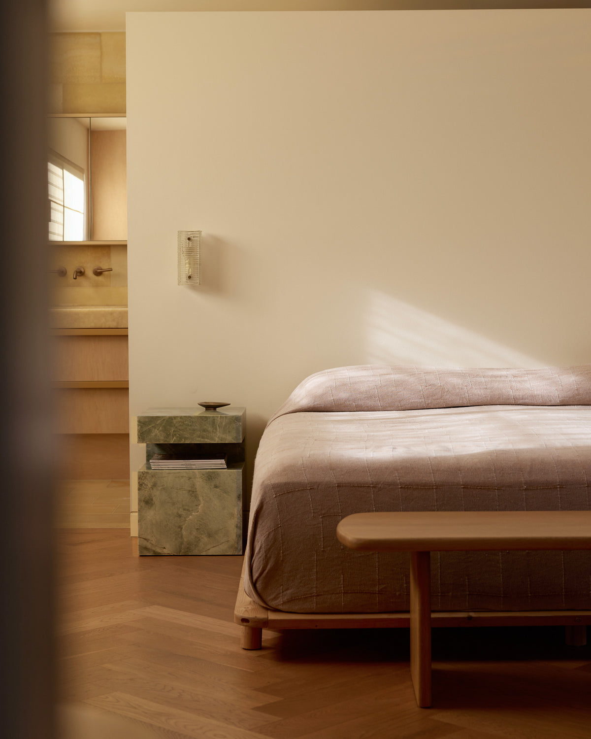 Bedroom with a bed, nightstand, and bench on a wooden floor.