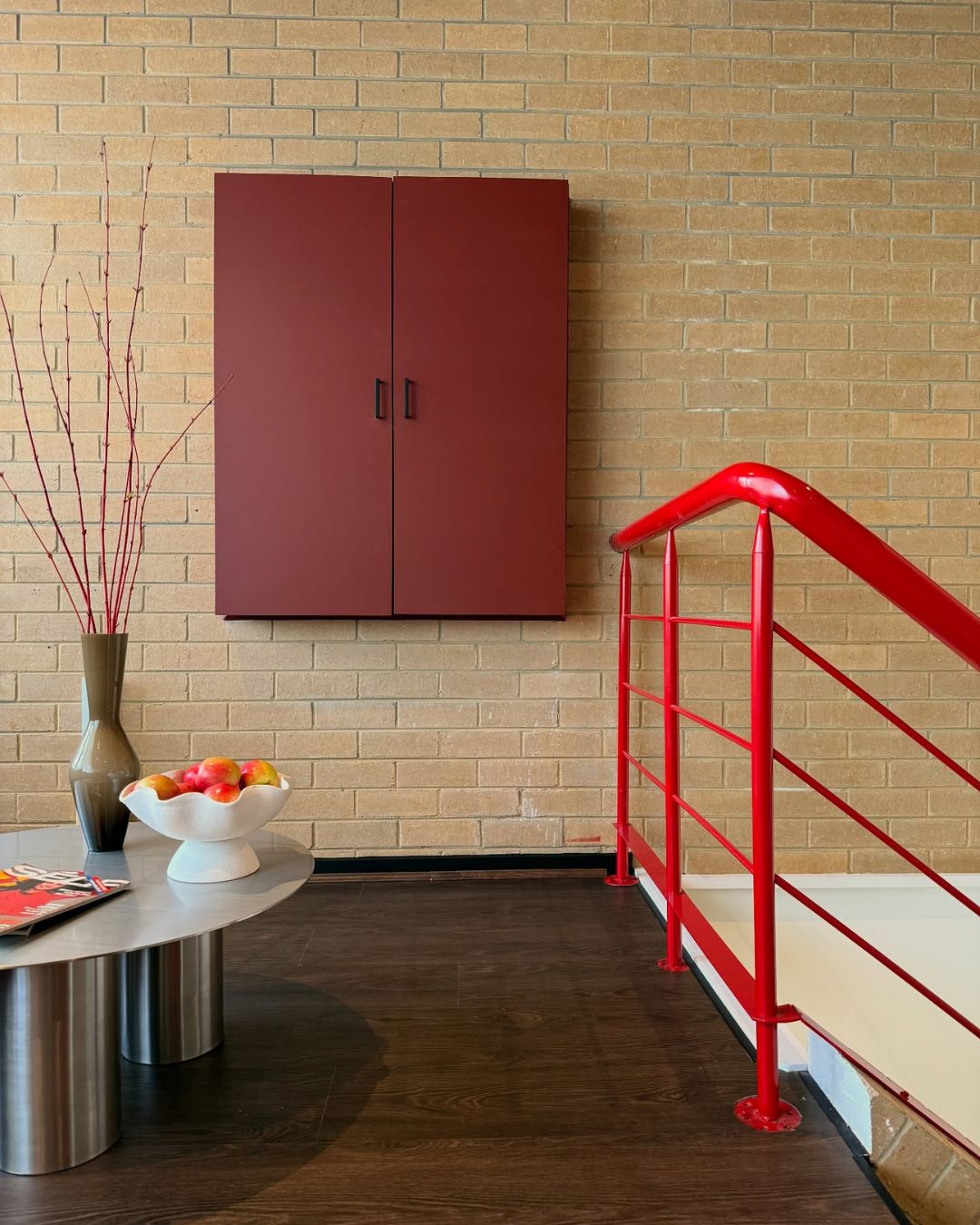 Modern interior with a red cabinet, red railing, and a coffee table.