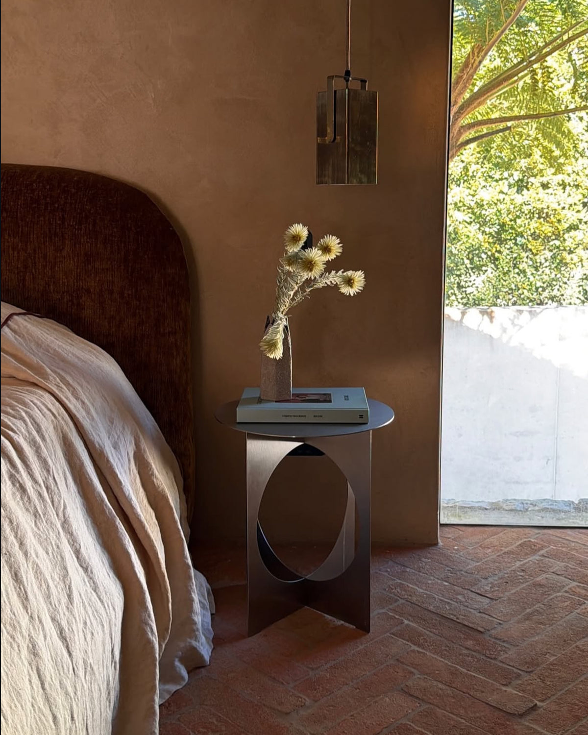 Stainless steel side table next to a bed